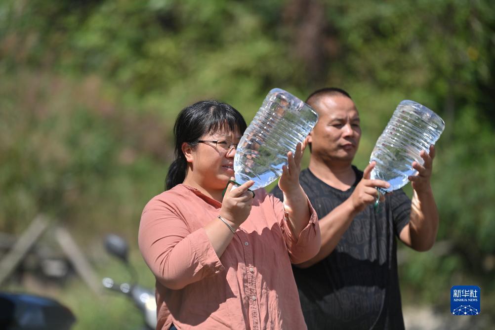 楊寧（左）在查看村民剛剛采集的水樣，為山泉水引水工程做準(zhǔn)備（10月8日攝）。新華社記者 黃孝邦 攝